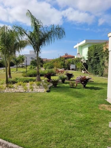 a yard with palm trees and a building at Sobrado com garagem e churrasqueira in Tijucas