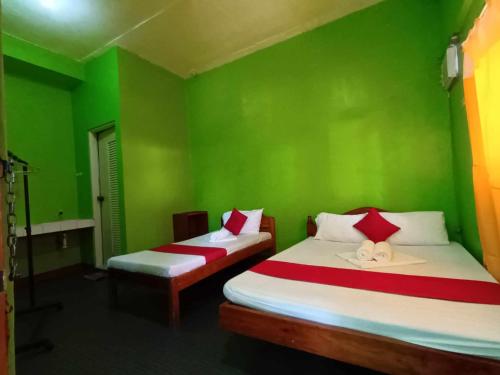 une chambre verte avec deux lits et un mur végétal dans l'établissement William Hearts Pension, à Puerto Princesa