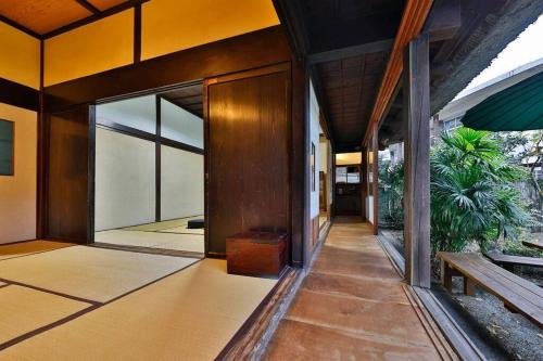 a hallway of a house with a door and a plant at 古民家さくらや in Atami