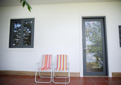 two chairs sitting in front of a door at LUA Farmstay in Ba Ria