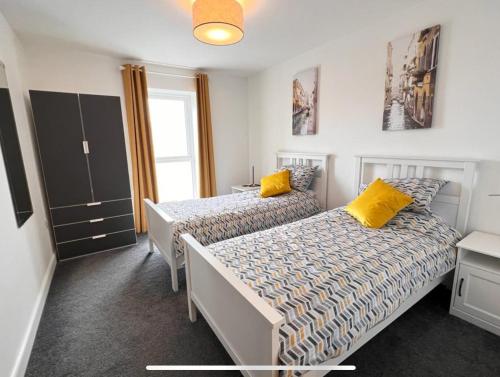 a bedroom with two beds with yellow pillows at Royal Atlantic View Apartment in Portrush