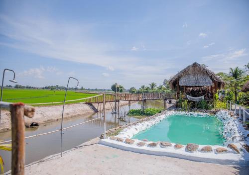 a swimming pool with a thatch hut and a swimming pool at LUA Farmstay in Ba Ria