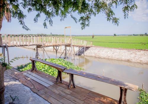 a wooden bench sitting on a boardwalk over a river at LUA Farmstay in Ba Ria