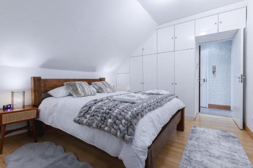 a white bedroom with a large bed and a table at Cosy Flat In London in Ealing