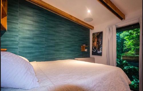 a bedroom with a large bed with a green wall at Condo VNV walking to Playa Guiones in Nosara