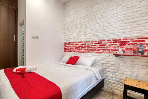 1 dormitorio con 1 cama con pared de ladrillo en RedDoorz Syariah @ Jl. Cengger Ayam Dalam, en Malang