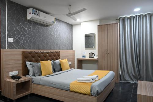 a bedroom with a bed with yellow and gray pillows at Supraja Cyber View in Hyderabad