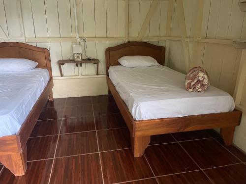2 camas en una habitación con suelo de madera en Amazilia, en Heredia
