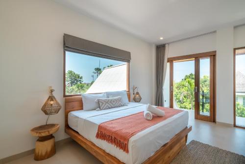 ein Schlafzimmer mit einem großen Bett und einem großen Fenster in der Unterkunft Villa Phan - Tranquil Stylish 2-Bedroom Villa in Pererenan in Munggu