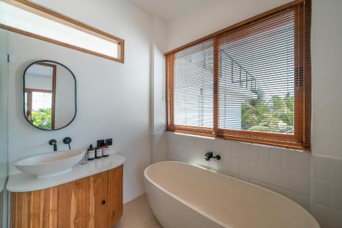 ein Badezimmer mit einer Badewanne, einem Waschbecken und einem Spiegel in der Unterkunft Villa Phan - Tranquil Stylish 2-Bedroom Villa in Pererenan in Munggu