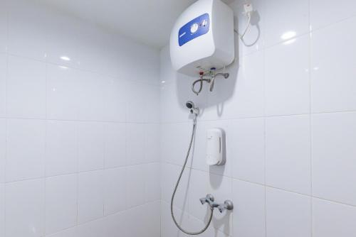 a shower in a white tiled bathroom at Urbanview Hotel Kazanan Lembang Bandung by RedDoorz in Bandung