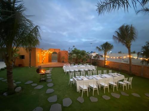 a group of white tables and chairs in a yard at Emirate Villa Mui Ne in Mui Ne