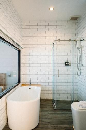 a white bathroom with a tub and a shower at Baan Tah On The Sea in Bang Sare