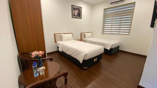 a room with two beds and a table and a window at Yên Tử Boutique Hotel in Yên Dương