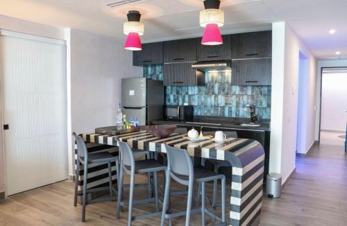 een keuken met een bar met stoelen en roze lampen bij Grant's Studio at Mantamar Tower in Puerto Vallarta