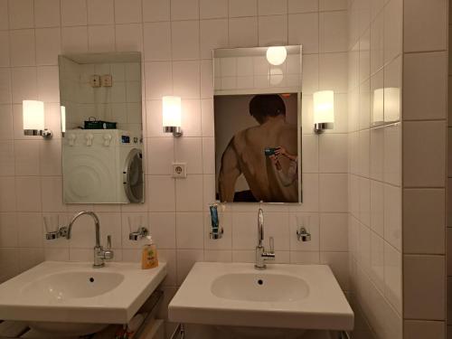 a bathroom with two sinks and a mirror and a person taking a picture at Sky Home Room 1 in Amsterdam