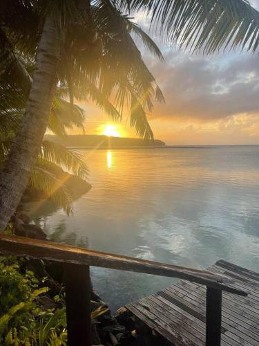 a sunset over the ocean with palm trees and a dock at Sale’aula Lava Studio Apartment in Saleaula