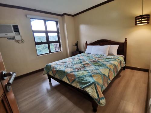 a bedroom with a bed and a window at Crosswinds Tagaytay Three Bedroom Suite in Tagaytay