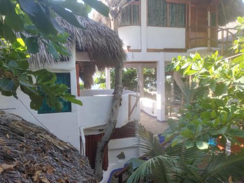 a white building with a thatch roof at Bambú Ecocabañas in San Agustinillo