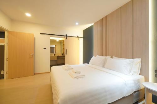 1 dormitorio con 1 cama blanca grande y toallas. en Alto Hotel M, en Mae Sot