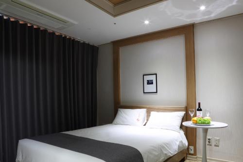 a bedroom with a bed and a table with a bottle of wine at Incheon The Hotel Yeongjong in Incheon