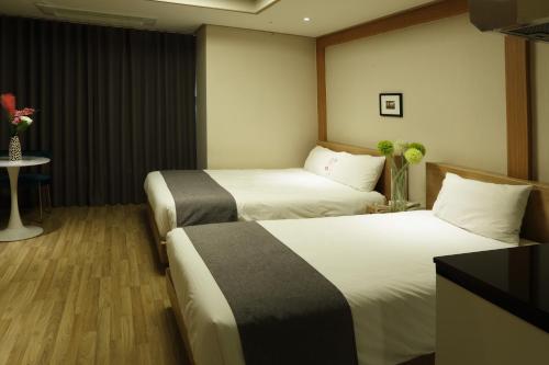 a hotel room with two beds and a table with flowers at Incheon The Hotel Yeongjong in Incheon