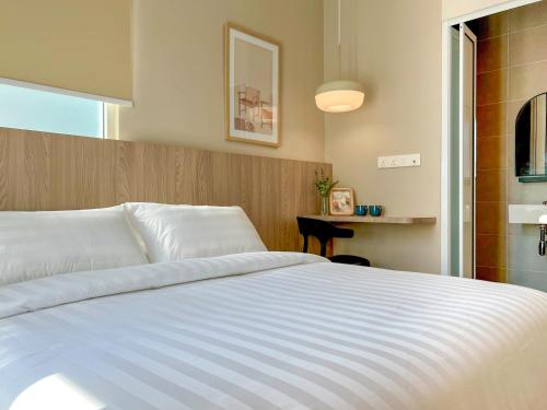 a bedroom with a large white bed in a room at La Vie Hotel Juru in Simpang Ampat