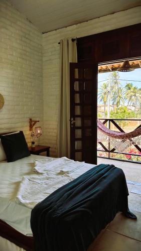 a bedroom with a bed and a door to a patio at Suítes Bosque de Flecheiras in Flecheiras