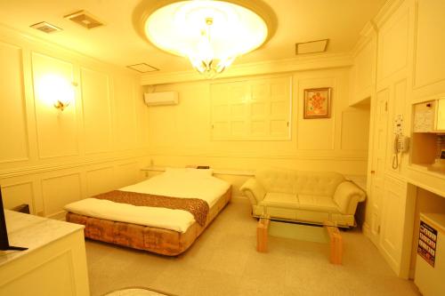 a bedroom with a bed and a couch and a chandelier at 水戸PARCO in Mito