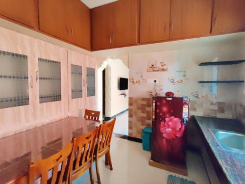 a kitchen with a table with chairs and a refrigerator at luxury home in Vadavalli in Coimbatore