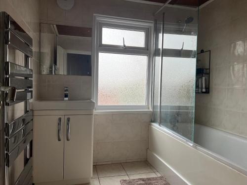 a bathroom with a shower and a tub and a window at Comfortable Single Room Wembley Park/Stadium in London