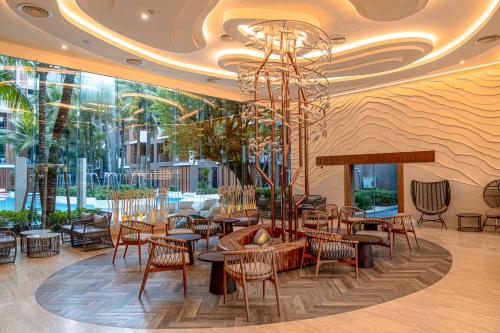 a restaurant with tables and chairs and a chandelier at The Marin Phuket Kamala Beach in Kamala Beach