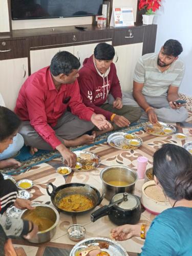 ジャナクプルにあるMithila Culture Janakpurdham Homestayの床に座って食べ物を食べる集団