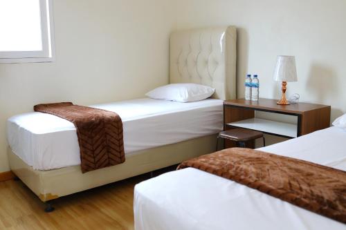 a hotel room with two beds and a table at Bungo Bed & Breakfast Workation in Bukittinggi