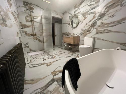 baño con bañera blanca y pared de mármol en Luxury Home In Mourne Mountains, en Mayobridge