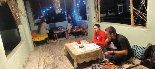 dwoje ludzi siedzących przy stole w pokoju w obiekcie Hotel Poonam Pushkar w mieście Pushkar