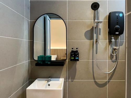 a bathroom with a shower and a sink and a mirror at La Vie Hotel Juru in Simpang Ampat