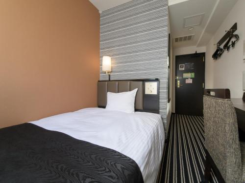 um quarto com uma grande cama branca num quarto em APA Hotel TKP Sapporo Ekimae em Sapporo