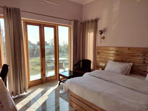 a bedroom with a bed and a large window at Shepherds Of Dharamshala in Dharmsala