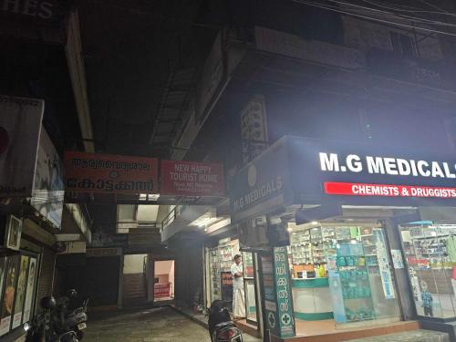 a store with signs on the side of a building at OYO Hotel NEW HAPPY TOURIST HOME in Muttam