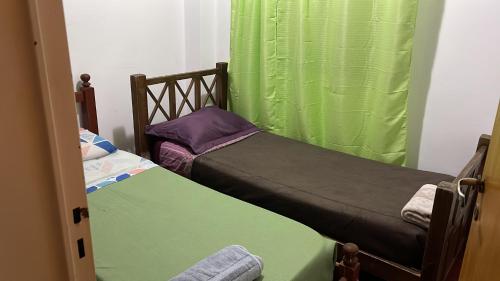 two twin beds in a room with green curtains at EL AMANECER - APART HUASI III in San Fernando del Valle de Catamarca