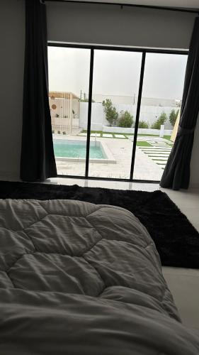 a bed in a bedroom with a view of a pool at The sunset farm in á¸¨aÅŸat al BidÄ«yah