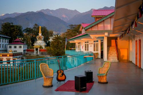 een balkon met stoelen en luidsprekers en bergen op de achtergrond bij Chokling ArtHouse - The Treasure of Himalayas in Bir