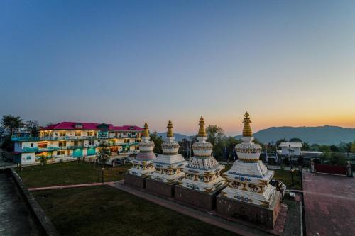 a view of a building with a sunset in the background at Chokling ArtHouse - The Treasure of Himalayas in Bīr