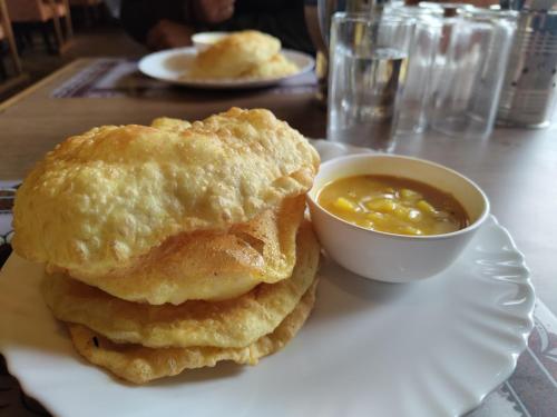 a plate with two biscuits and a bowl of dipping sauce at Hotel Vandana Palace in Surendranagar