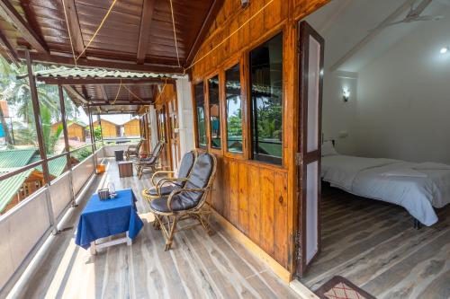 a room with a bed and a chair on a porch at Hitide Beach Resort in Palolem