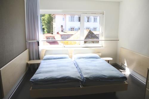 een kleine kamer met 2 bedden voor een raam bij Richemont Hotel in Luzern