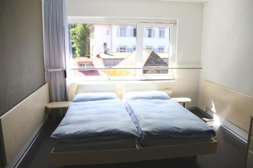 ルツェルンにあるリシュモン ホテルの窓の前にベッド2台が備わる小さな客室です。