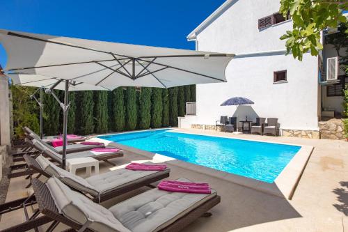 una piscina con sillas y una sombrilla junto a una casa en Family House Rose with Pool - Happy Rentals, en Pinezici