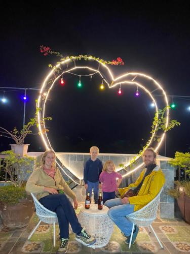 a family sitting in chairs under a heart with lights at Hang Múa Green Mountain View House in Ninh Binh
